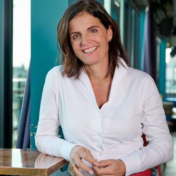 Porträt von Anne, Unterstützerin der genannten sozialen Initiativen, im Business-Casual-Look