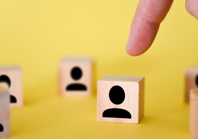 Workforce Transformation: Hand ordnet Holzfiguren als Symbol für veränderte Rollen in der Organisation